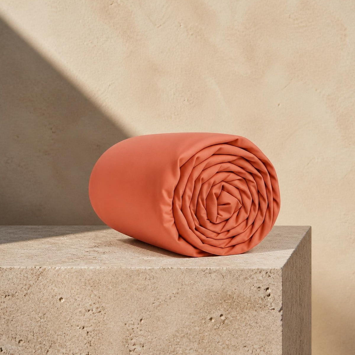 Spannbettlaken in Rosé 600 TC aus ägyptischer Baumwolle, gerollt auf Travertin