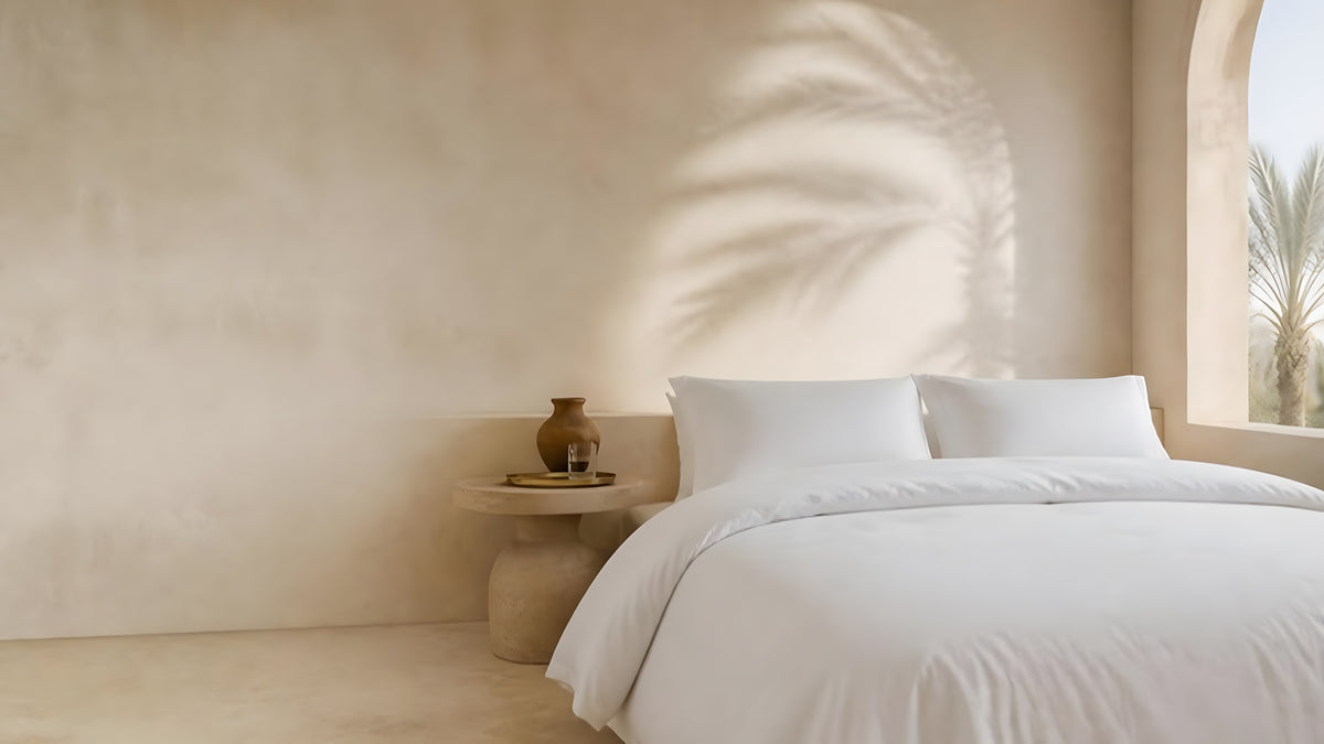 Weiße Satin-Bettwäsche aus ägyptischer Baumwolle in einem hellen Kalksteinschlafzimmer mit Palmenschatten